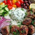 Greek Meatball Bowl with fluffy rice, cucumbers, tomatoes, red onion, olives, and tzatziki sauce