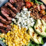 Grilled Balsamic Steak Salad topped with sliced steak, roasted corn, walnuts, and blue cheese