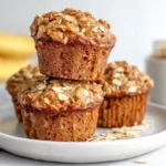 Healthy banana oatmeal muffins stacked on a plate with oats topping
