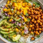 Mango Chickpea Salad with rice, avocado slices, cucumber, and tangy dressing