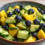 Mango cucumber salad with avocado and blueberries in a bowl