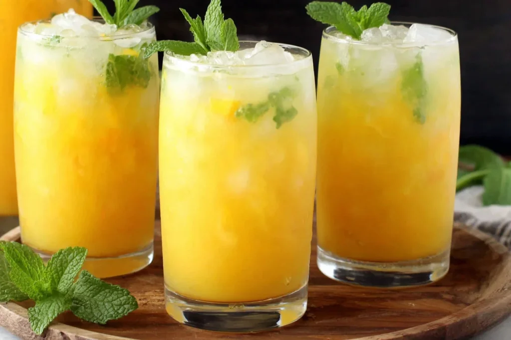 Refreshing Homemade Mango Lemonade in tall glasses with crushed ice and mint leaves