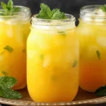 Refreshing Homemade Mango Lemonade served in mason jars with fresh mint and ice