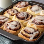 Golden Sourdough Discard Cinnamon Rolls in pan topped with vanilla glaze