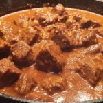 Close-up of Carne Guisada with flour tortillas featuring juicy beef chunks in thick Tex-Mex gravy