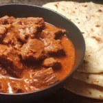 Carne Guisada with flour tortillas served in a black bowl with tender beef and rich savory gravy