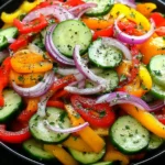Cucumber Sweet Pepper Salad served in a black bowl with cucumbers, sweet bell peppers, red onion, and fresh herbs