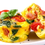 Egg Muffins with Spinach and Feta Recipe served with fresh tomatoes and spinach on a white plate