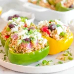 Greek Chicken Stuffed Peppers served on a plate with feta, olives, rice, and fresh herbs, garnished with dill and lemon
