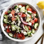 Greek Cucumber Salad with feta, olives, tomatoes, and red onions in a white bowl