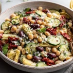 Mediterranean Three Bean Salad with chickpeas, kidney beans, cucumbers, sun dried tomatoes, and artichokes in a large serving bowl