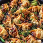 Potsticker Stir Fry with crispy dumplings, broccoli, mushrooms, and sesame sauce in a black skillet