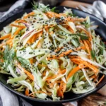 Simple Easy Cabbage and Carrot Salad with creamy mustard dressing, fresh dill, and black sesame seeds in a black bowl
