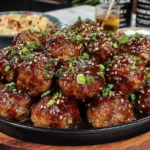 Sticky Hoisin Meatballs with Scallion Sauce served with sesame seeds and chopped scallions
