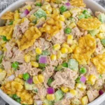 Close-up of Viral Tuna Salad with corn, peas, red onion, and crispy chips in creamy dressing