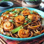 Yaki Udon with Shrimp in a blue bowl with stir-fried udon noodles, shrimp, onions, and scallions