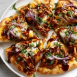 BBQ Chicken Flatbread Recipe topped with shredded chicken, melted cheese, red onion, and fresh cilantro on a crispy flatbread