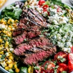 Balsamic Steak Gorgonzola Salad served with grilled corn, sliced sirloin steak, cherry tomatoes, red onion, and Gorgonzola crumbles