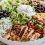 Chipotle Burrito Bowl served with grilled chicken, cilantro lime rice, guacamole, black beans, corn salsa, pico de gallo, and fresh lettuce