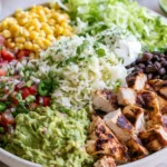 Chipotle Burrito Bowl with grilled chicken, cilantro lime rice, black beans, fresh tomato salsa, corn salsa, guacamole, and sour cream