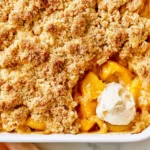 Easy Peach Cobbler baked until golden brown with fresh peaches, crunchy crumble topping, and vanilla ice cream