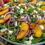Fresh Peach Arugula Salad with goat cheese, pecans, red onion, and balsamic dressing served in a bowl