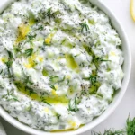 Healthy Tzatziki Sauce made with Greek yogurt, cucumber, fresh dill, lemon, and olive oil in a white serving bowl