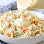 Homemade Coleslaw Dressing being poured over fresh cabbage slaw for a creamy side dish