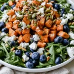 Honey Sweet Potato Summer Salad topped with roasted sweet potatoes, blueberries, goat cheese, pepitas, and pine nuts
