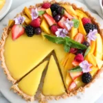 Mango Curd Tart Recipe with a sliced piece removed, revealing creamy mango curd filling and a golden tart crust