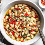 Marinated White Beans with fresh herbs, roasted red peppers, garlic, and olive oil served in a rustic bowl