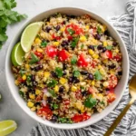 Southwest Quinoa Salad served with black beans, corn, tomatoes, cilantro, and fresh lime wedges