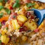Aloha Pineapple Chicken Rice Casserole served on a spoon with juicy chicken, caramelized pineapple chunks, rice, bacon, and fresh herbs