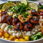 Chicken Mango Rice Bowl with grilled chicken, mango salsa, avocado, and spicy sauce over rice
