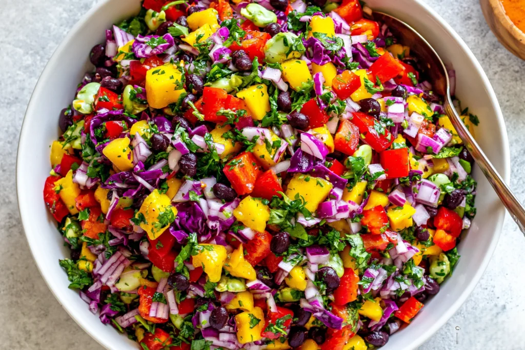 Fresh Black Bean Mango Salad with vibrant mango chunks, black beans, red cabbage, bell peppers, and cilantro in a bowl