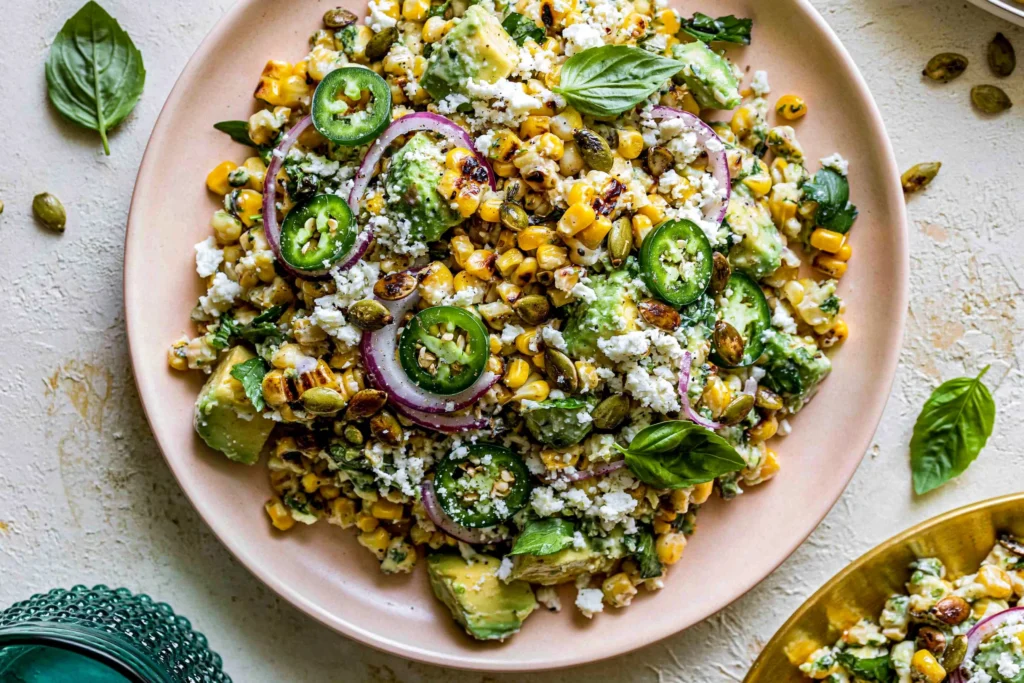 Fiesta Avocado Corn Salad with charred corn, avocado chunks, jalapeño slices, Cotija cheese, and fresh herbs in a rustic bowl