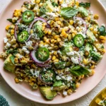 Fiesta Avocado Corn Salad with charred corn, avocado chunks, jalapeño slices, Cotija cheese, and fresh herbs in a rustic bowl