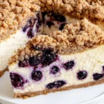 Close-up slice of Blueberry Crumble Cheesecake with creamy texture, fresh blueberries, and golden buttery crumble topping