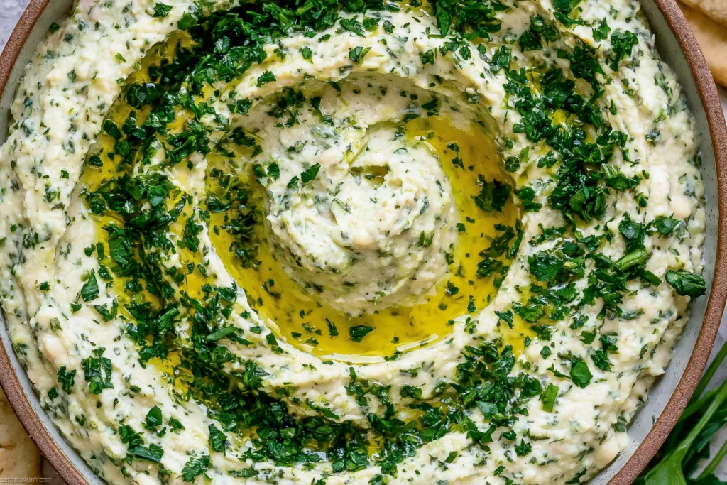 Close-up of creamy Lemon & Herb White Bean Dip swirled with olive oil and topped with fresh chopped herbs