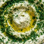 Close-up of creamy Lemon & Herb White Bean Dip swirled with olive oil and topped with fresh chopped herbs