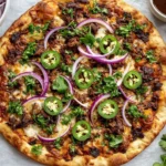 Crispy oven-baked Birria Pizza topped with melted cheese, shredded beef, red onion, jalapeños, and fresh cilantro