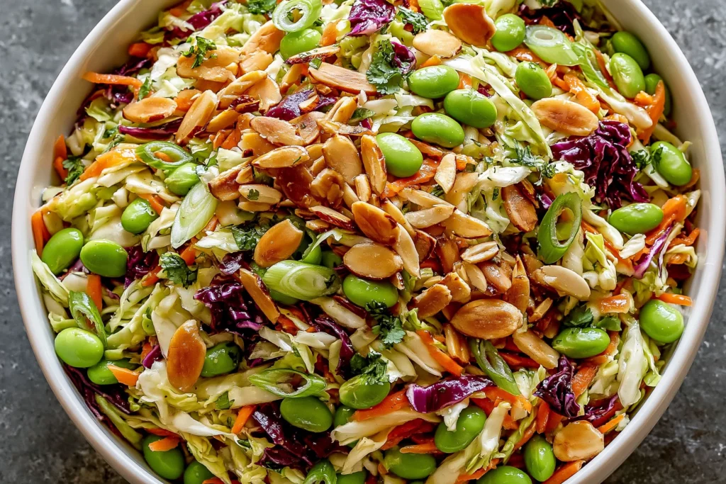 Crunchy Cabbage and Edamame Salad with sesame ginger dressing, toasted almonds, shredded cabbage, carrots, and green onions