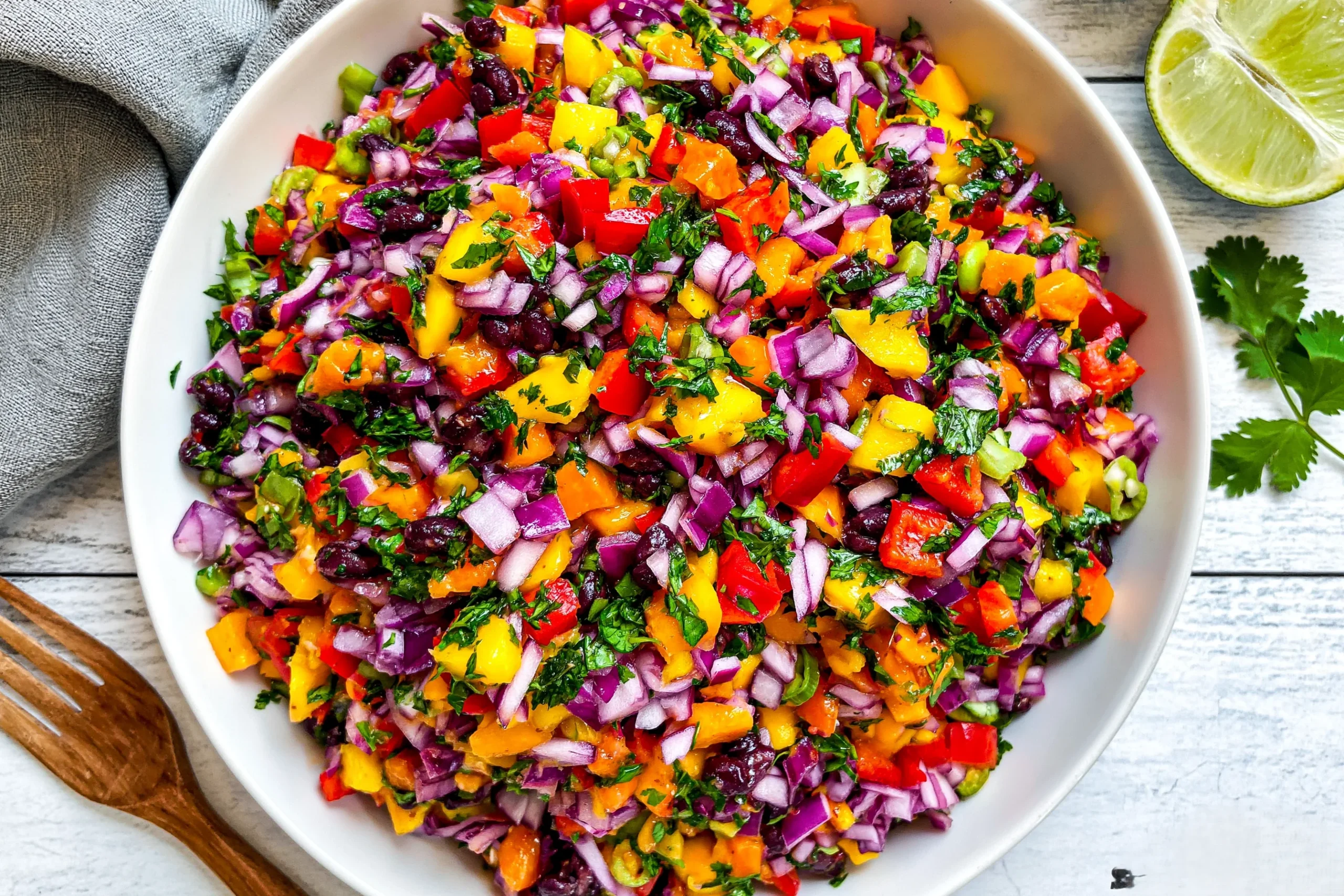 Colorful Black Bean Mango Salad with diced mango, black beans, red onion, bell peppers, and fresh cilantro in a bowl