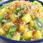 Pineapple Kiwi Salad with toasted coconut, fresh mint, and honey lime dressing in a bowl