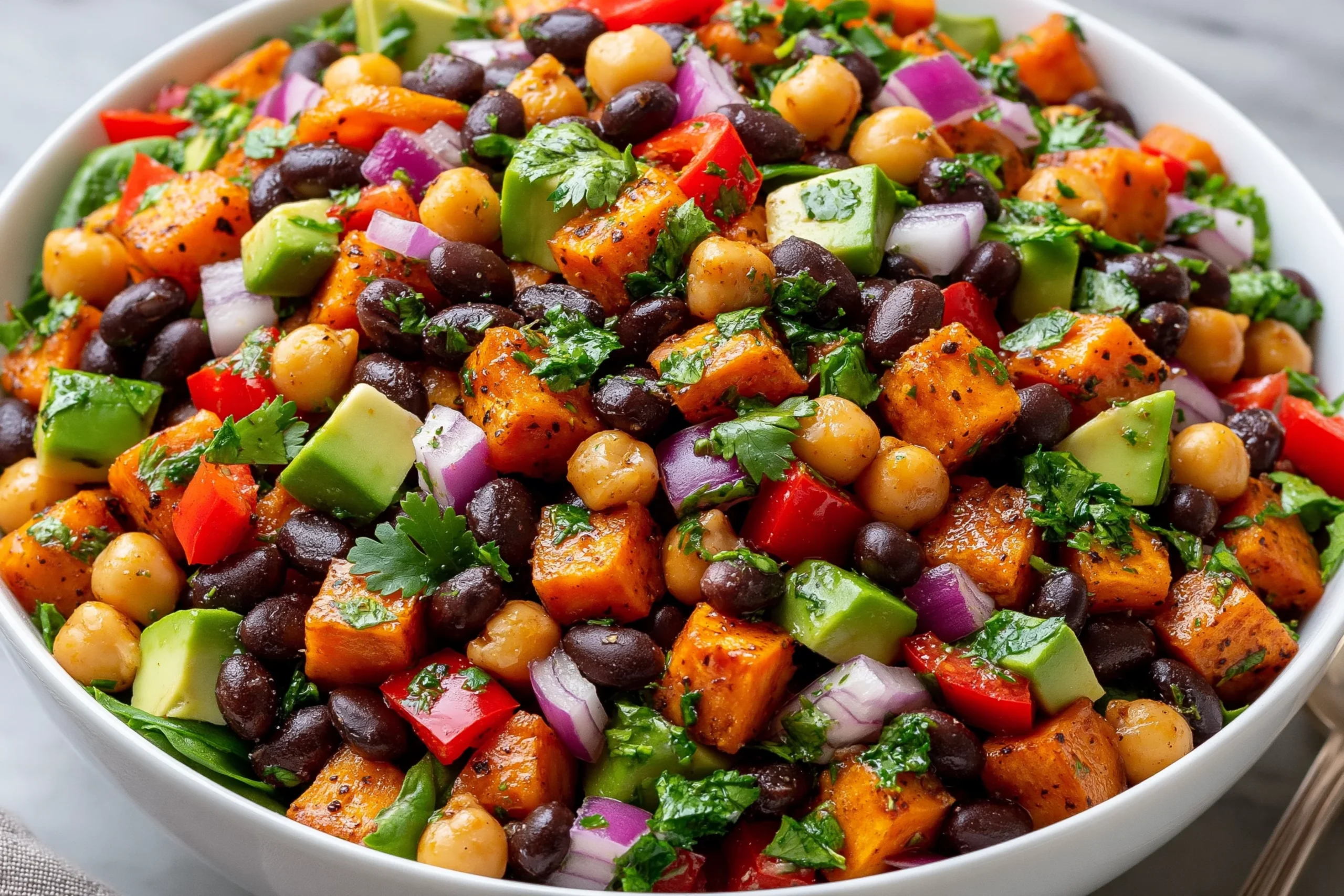 Sweet Potato Black Bean and Chickpea Salad with roasted sweet potatoes, avocado, bell peppers, and fresh cilantro in a vibrant bowl
