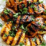 Close-up of Hawaiian Chicken with Coconut Rice featuring grilled pineapple rings, glazed chicken, and fresh parsley over fluffy rice
