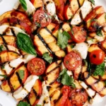 Peach Caprese Salad with grilled peaches, fresh mozzarella, cherry tomatoes, basil, and balsamic glaze on a white plate