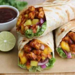 Hawaiian BBQ Chicken Wraps with grilled BBQ chicken, pineapple chunks, lettuce, and red onion in soft tortillas served with dipping sauce