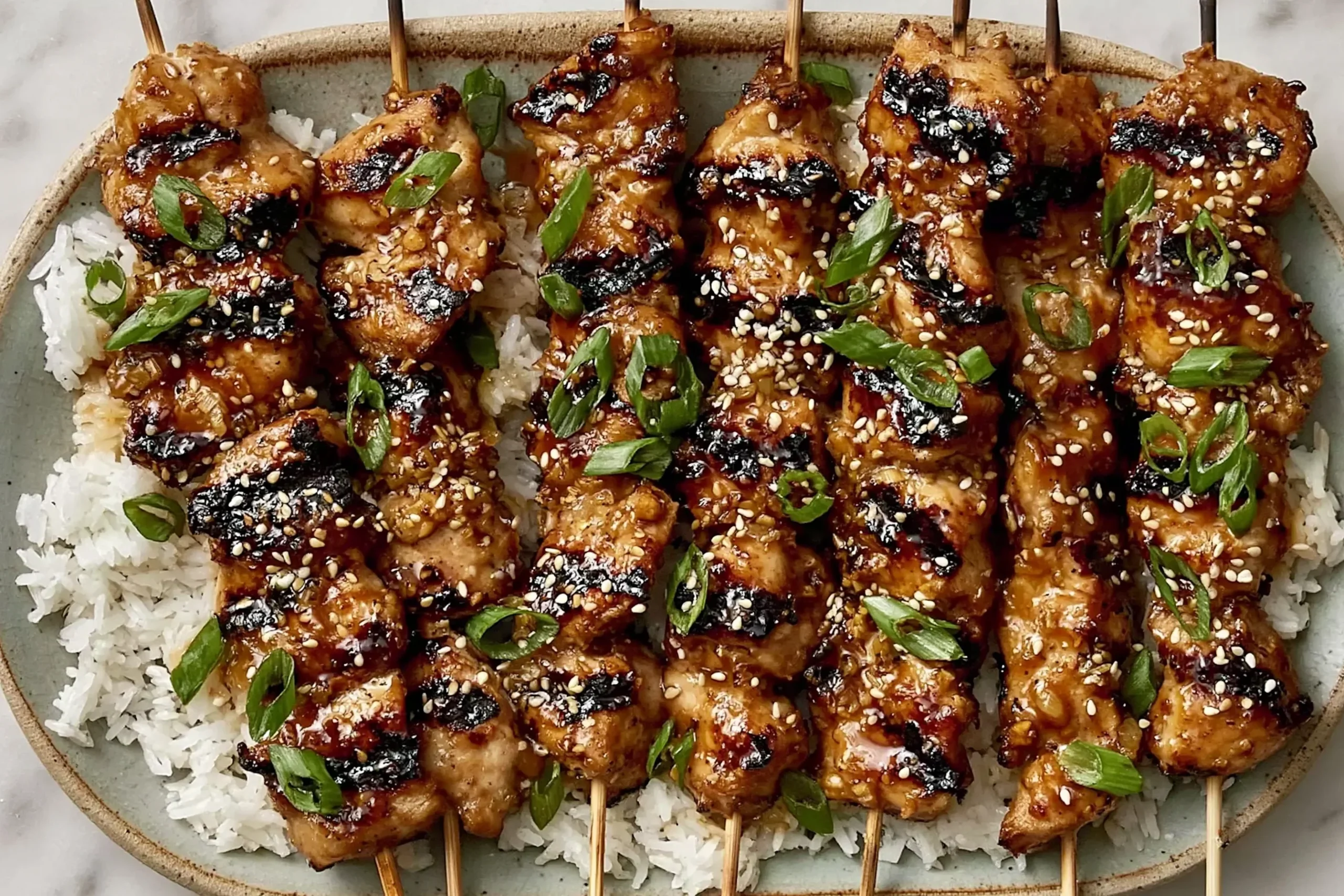 Honey Garlic Asian Chicken Kabobs grilled with sesame seeds and green onions served over rice with a glossy glaze
