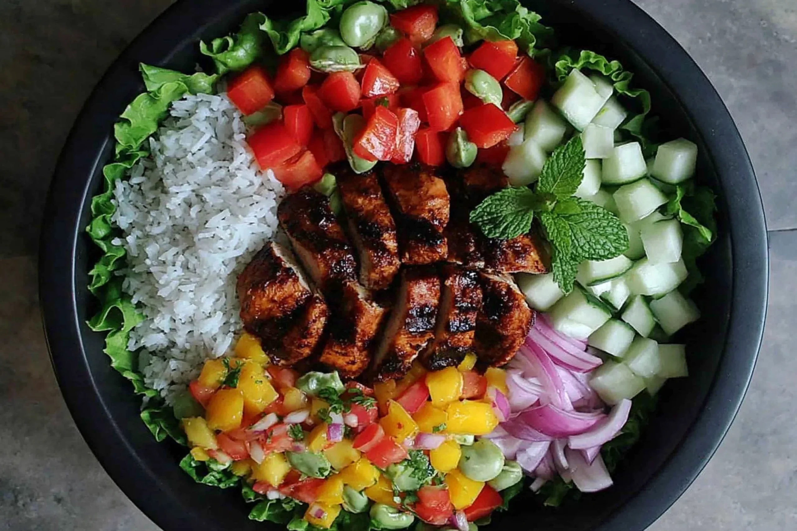 Jerk Chicken Buddha Bowl with Mango Salsa served with rice, fresh vegetables, and grilled spicy chicken